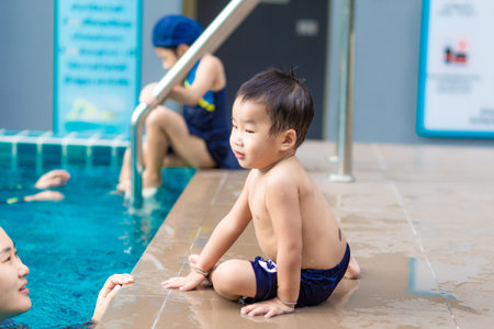 Happy kindergarten asian boy swimming with mom in condominium swimming pool outdoor activityの写真素材