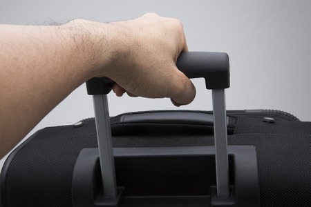 Hand hold a Black suitcase isolated on white background