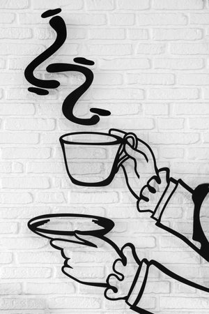 Hand holding a coffee mug on a white painted brick wall backgroundの写真素材