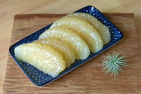 Pomelo slices in a blue plate on woodenの写真素材