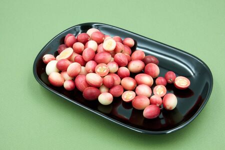 Carandas plum ,Carissa carandas Linn.,sour taste fruit on black plate,green paper backgroundの写真素材