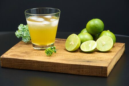 Thai Lime,honey mixed lime juice in a clear glass,wooden plate,black backgroundの写真素材