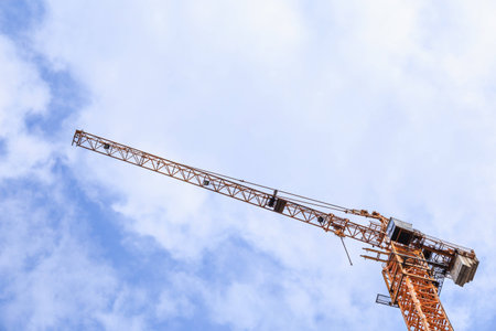 Construction crane, blue sky, and white cloud from an ant eye viewの写真素材