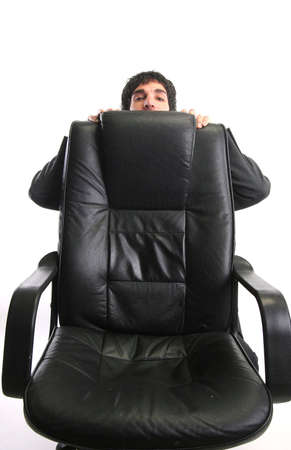 businessman hiding behind his chairの写真素材