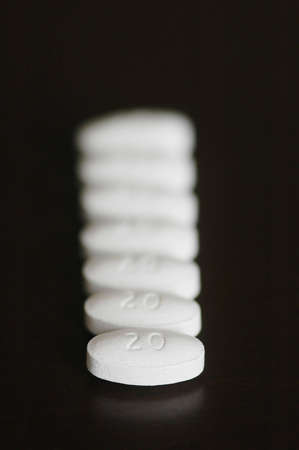 white pills in a long line, the one in th efront is in focus