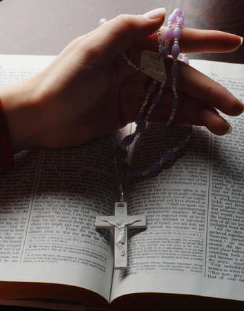 holy bible open with a cross on a hand