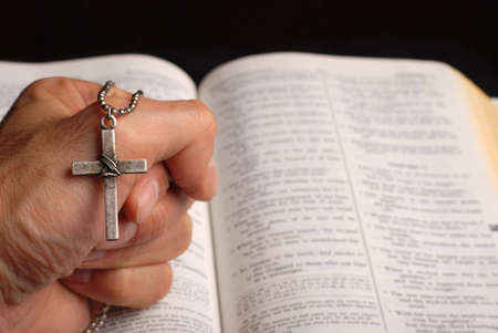 holy bible open with a cross on a hand