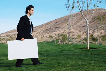 confident and successful businessman is holding a blank boardの写真素材