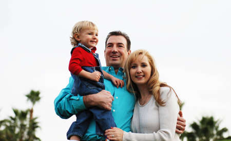 happy couple with a child  smiling in green park environmentの写真素材