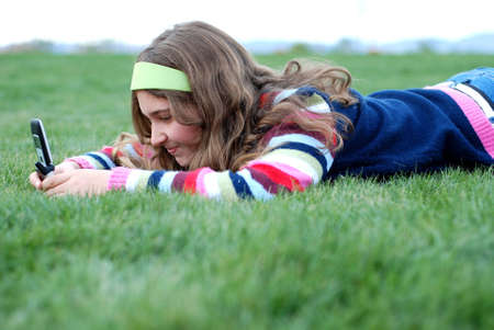 young blond girl in the park and cell phoneの写真素材