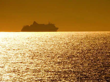 A summer golden Sunset beneath a passenger ship crossing the horizon  in Mediterranean Sea near Athens Greece June 25 2021の写真素材