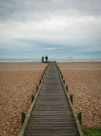 2 people together at the end of a boardwalk across Dungeness beachの写真素材
