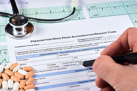 Human fill Prescription drugs prior authorization request form, pills, stethoscope on a EKG graph...