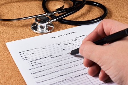 Human fill a Medication request form on corkwood and stethoscope background. Close-up.の写真素材