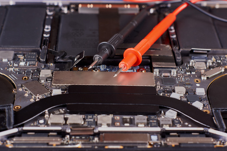 Probes of tester and disassembled laptop in an aluminum case on a blue velvet background. Close-up