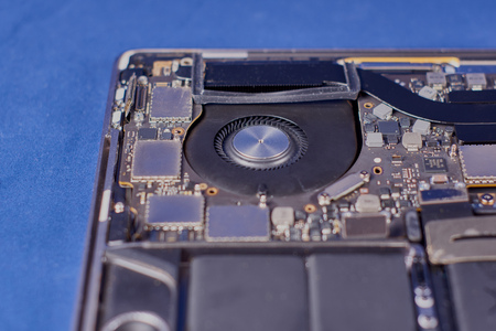 Part of a disassembled laptop with a fan in an aluminum case on a blue velvet background. Close-upの写真素材