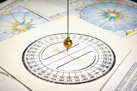 Astrological pendulum for tarot and astrological circle on the background of astrological charts and horoscopesの写真素材