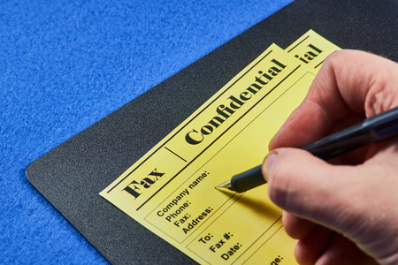Human fills confidential fax forms on a blue velvet background. Close-up