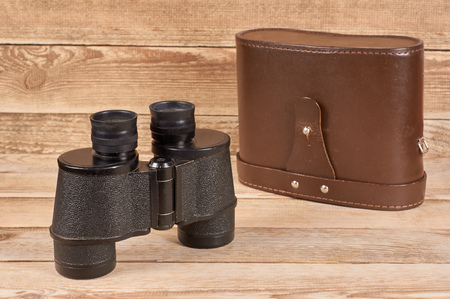 Ancient army binoculars with a case on a wooden backgroundの写真素材