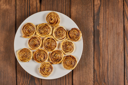 puff cookie with chocolate layer on white plate on wood background, flat layの写真素材