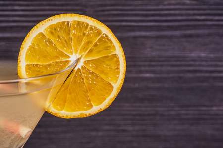 Orange slice on the edge of the martini glass, on a dark wooden background. Close-upの写真素材