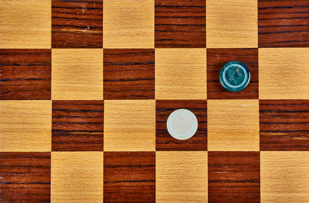 One marble checker and one malachite checker on a wooden checkerboard. Flat layの写真素材