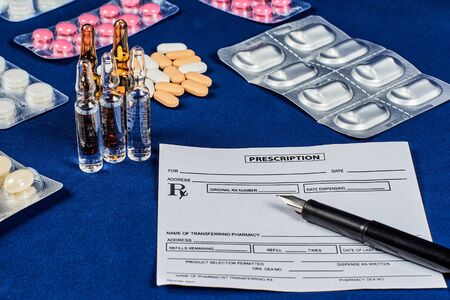 prescription, pen, tablets and ampoules on a blue velvet backgroundの写真素材