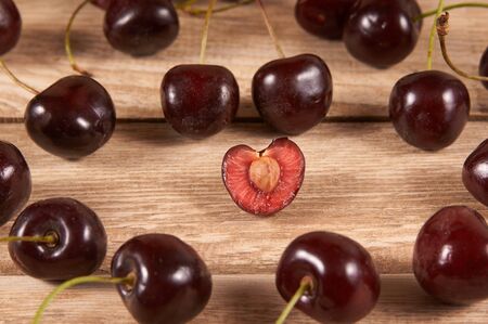 opened cherry with a ossicle, several cherries are diffuse on a wooden background