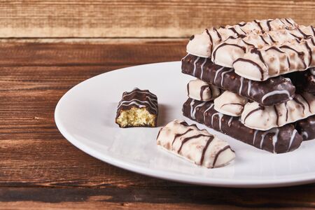 One broken cookie and long sticks shortbread cookies in dark and white chocolate icing on a white...