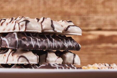 Long sticks shortbread cookies in dark and white chocolate icing on a white plate on wooden background. Close-upの写真素材