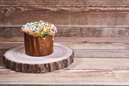 Easter composition. Easter cake on a stand made of a slice wood on a light wooden background. With...