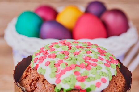 Easter composition. Easter cake on a stand made of a slice wood and a white basket on wheels with...
