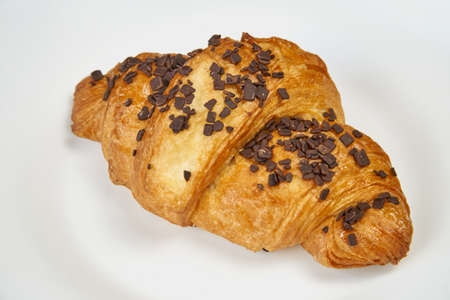 Croissant with chocolate sprinkles lies on a white plate. Isolated on whiteの写真素材