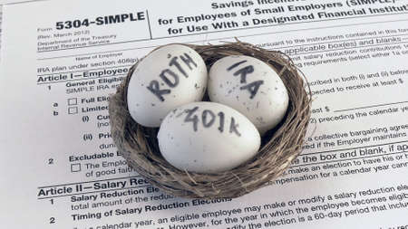 Conceptual composition. Pension savings. Individual retirement account. Three eggs with the inscriptions IRA, 401k, Roth lie in the nest against the background of the 5304-SIMPLE form. Close-upの写真素材