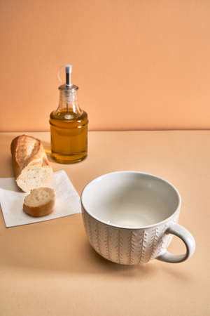 An empty soup mug stands on the table next to spices and breadの写真素材