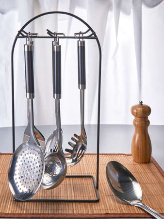 Kitchen utensils. Noise, ladle and other devices stand in a stand on a bamboo napkin next to the pepperingの写真素材