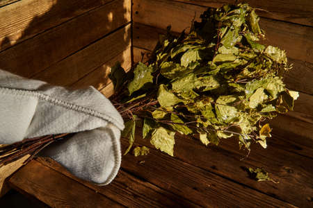 Bath supplies. A man in a mitten holds a birch broom in his handの写真素材