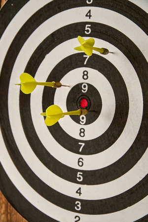 Darts game. Throwing darts at the target. Three yellow darts hit the target. Close-up