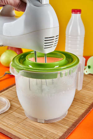 Someone whips milk in a transparent cup with a mixer. Mixer whisk rotate close-upの写真素材