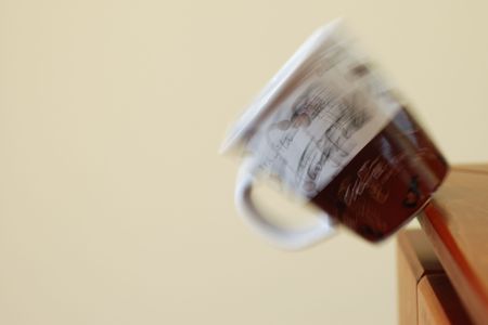 Coffee mug falling off the edge of a tableの写真素材
