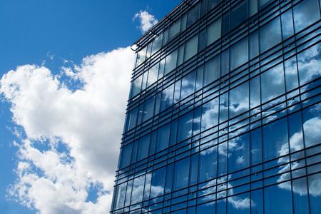 A view of office building windows reflecting the sky and clouds