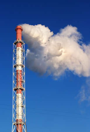 A smoking factory chimney over a blue sky