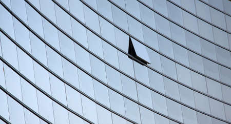 An open window in a row of similar dark office windows depicting a uniqueness conceptの写真素材