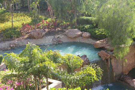 An artificial waterfall in a nice sunny tropical gardenの写真素材