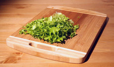 Cut lettuce leaves on a wooden board on a kitchen tableの写真素材