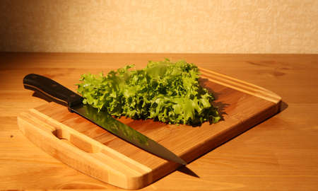 Lettuce leaves on a cutting board and a long knifeの写真素材