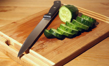 Parts of a cut cucumber on a cutting board and a knifeの写真素材