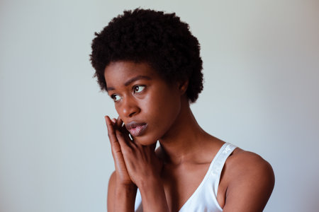 Portrait of a thoughtful young woman standing against grey background in studioの写真素材