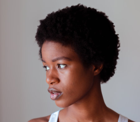 Portrait of a young african american woman looking away against grey backgroundの写真素材