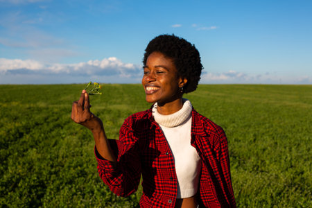 young african american woman holding grasshopper in green fieldの写真素材